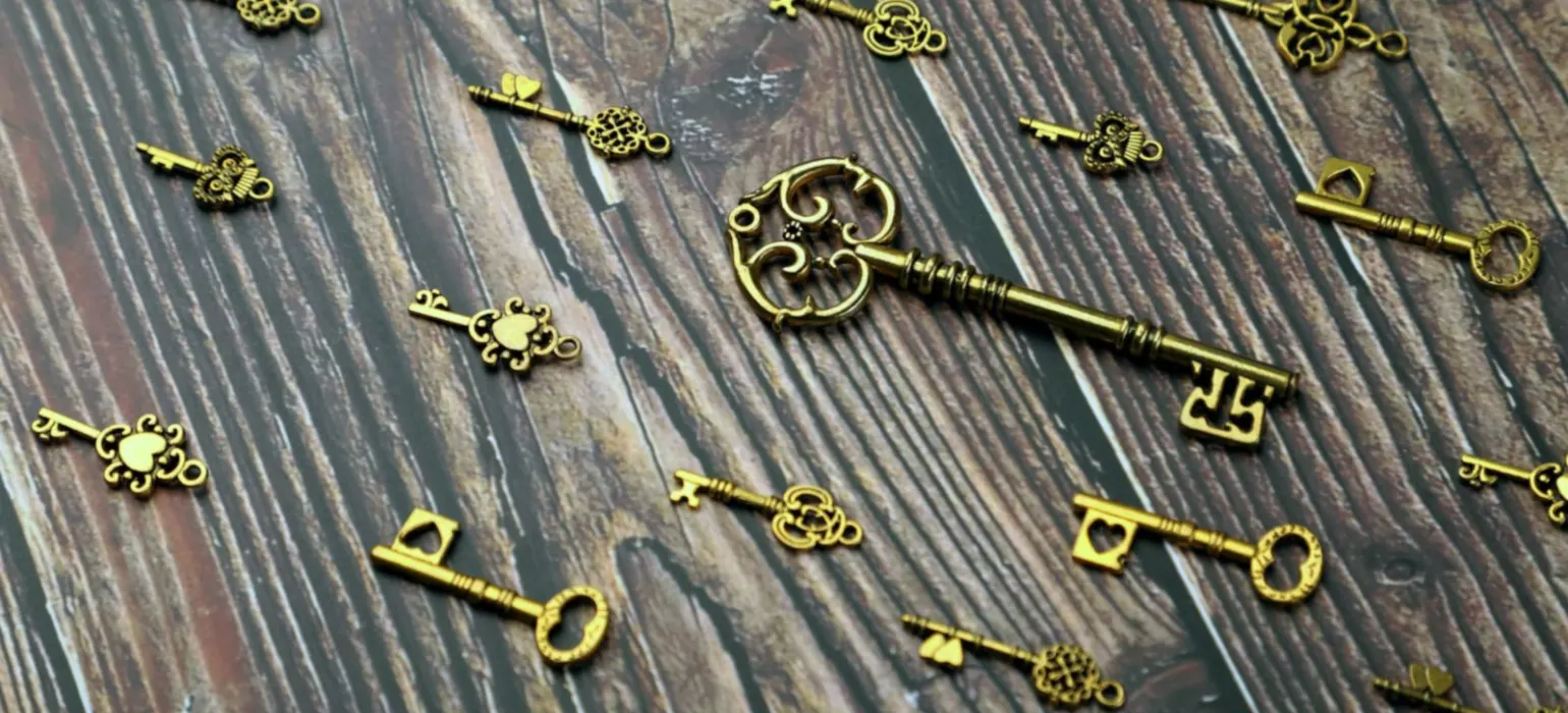 Silver and gold skeleton key on wooden surface