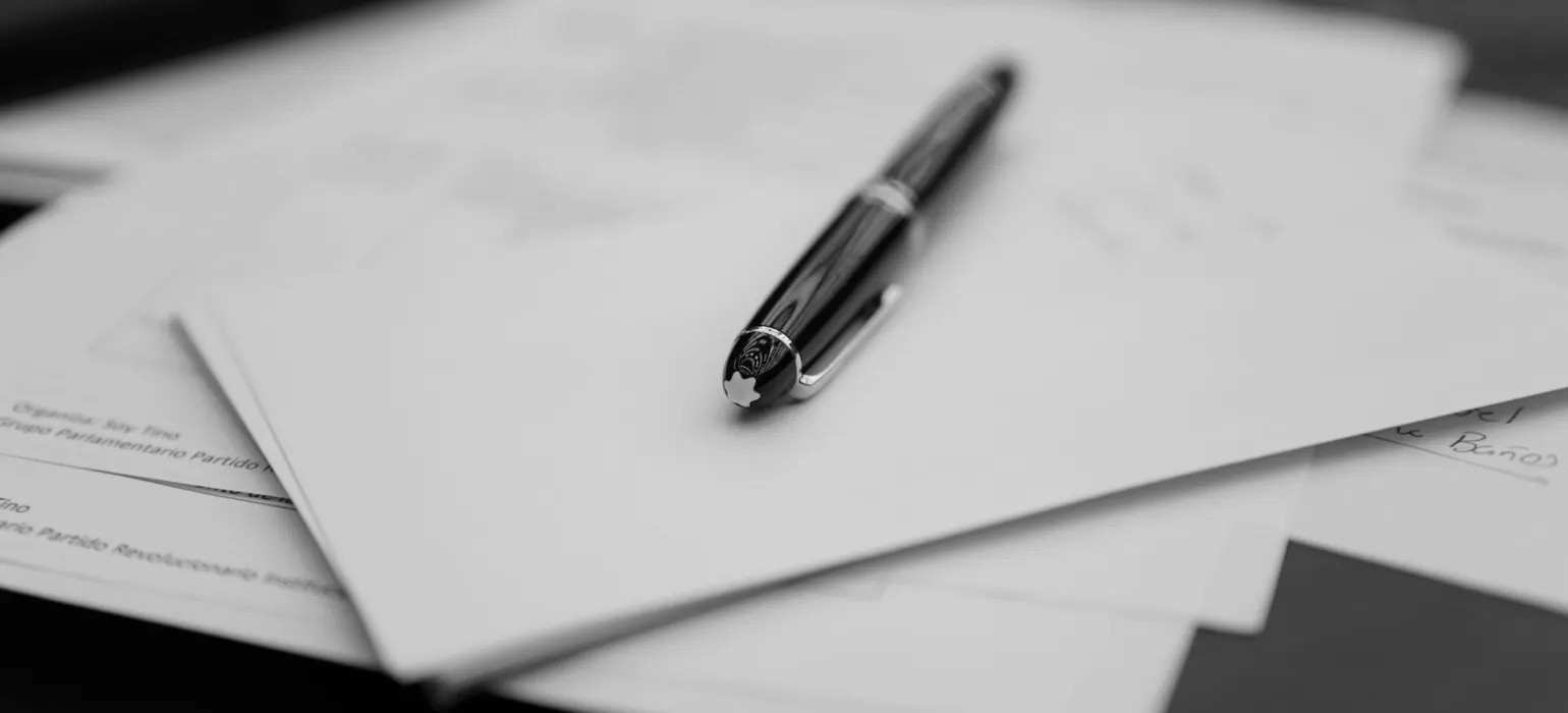 A pen sitting on top of a pile of papers