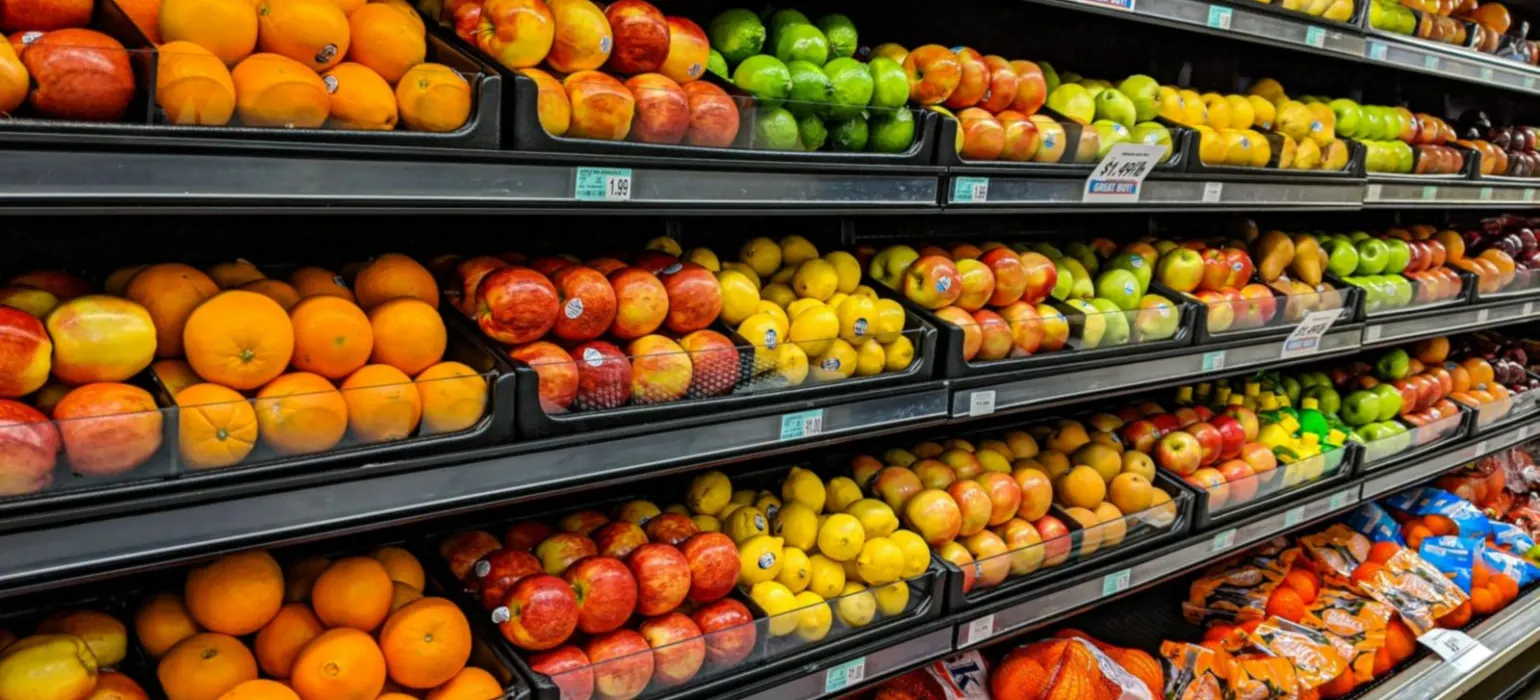 Shelves of fresh oranges, apples, lemons, and limes in a grocery store