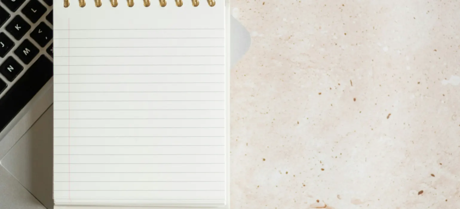 A notepad sitting on top of a laptop computer next to a keyboard