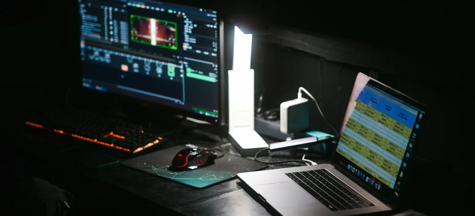 A laptop and a computer monitor on a dark desk in a workspace