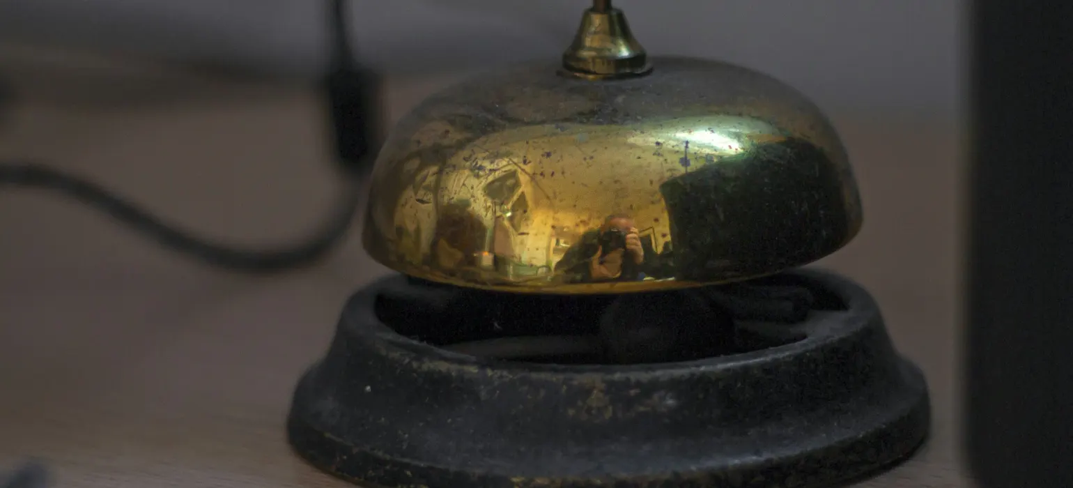 A vintage brass service bell on a wooden desk