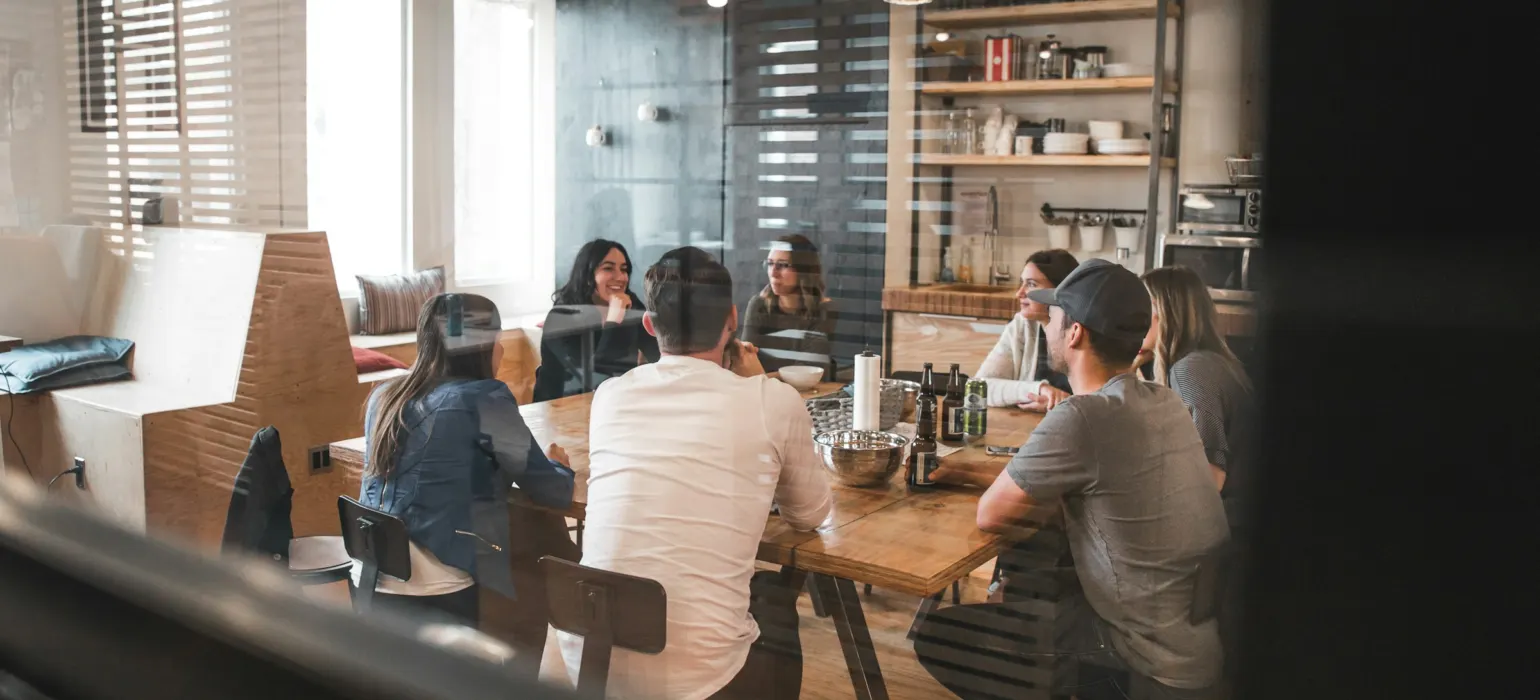 Customers seated around a table in a busy restaurant