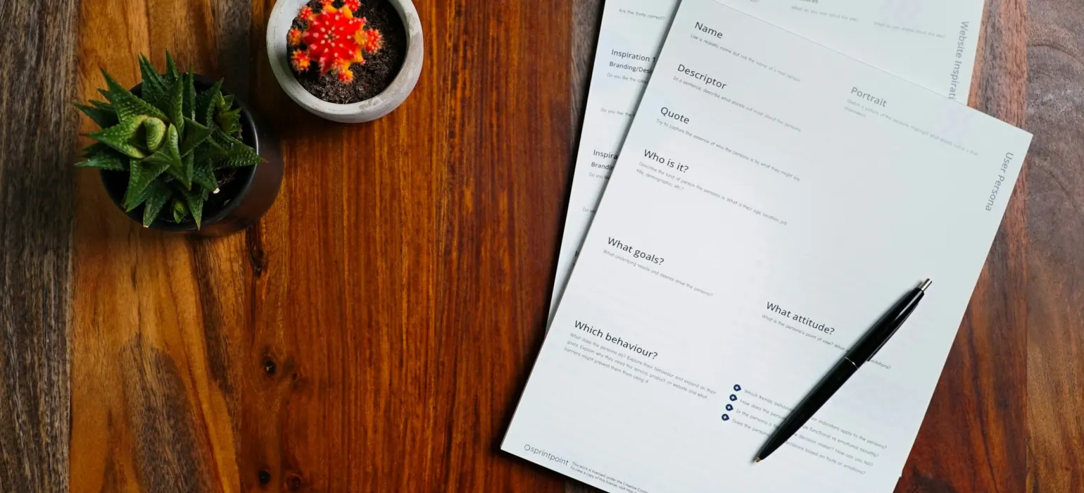 A wooden table topped with papers and a pen
