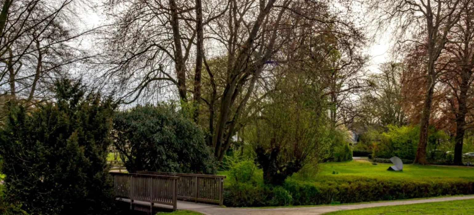 A park path leading to a wooden bridge over grass