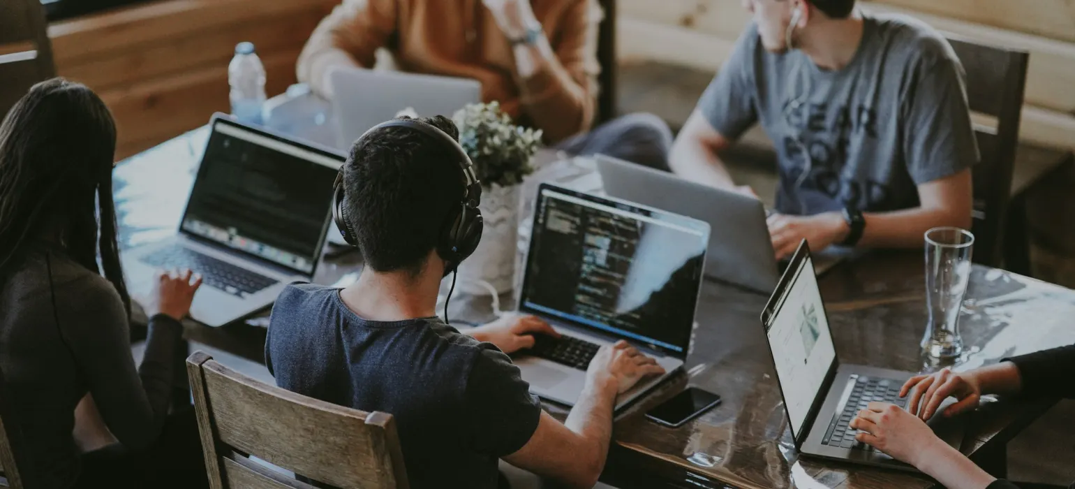 Software team working on laptops around a table