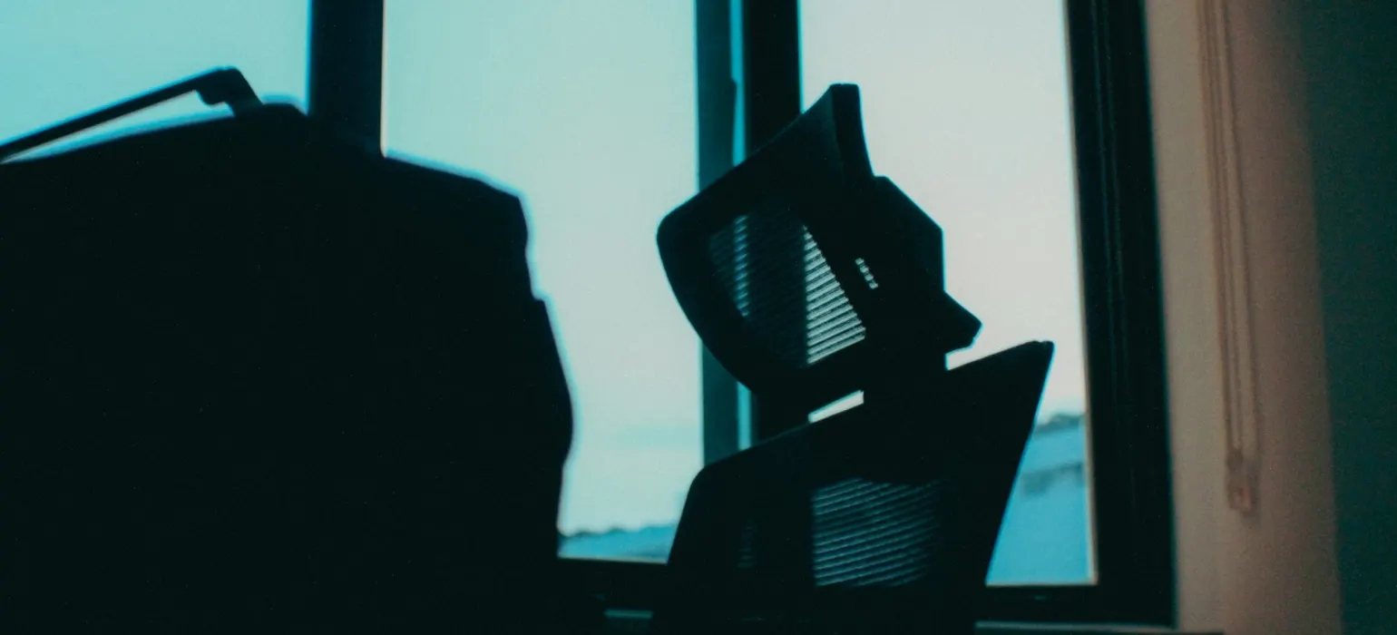Laptop and chair silhouetted against a bright window