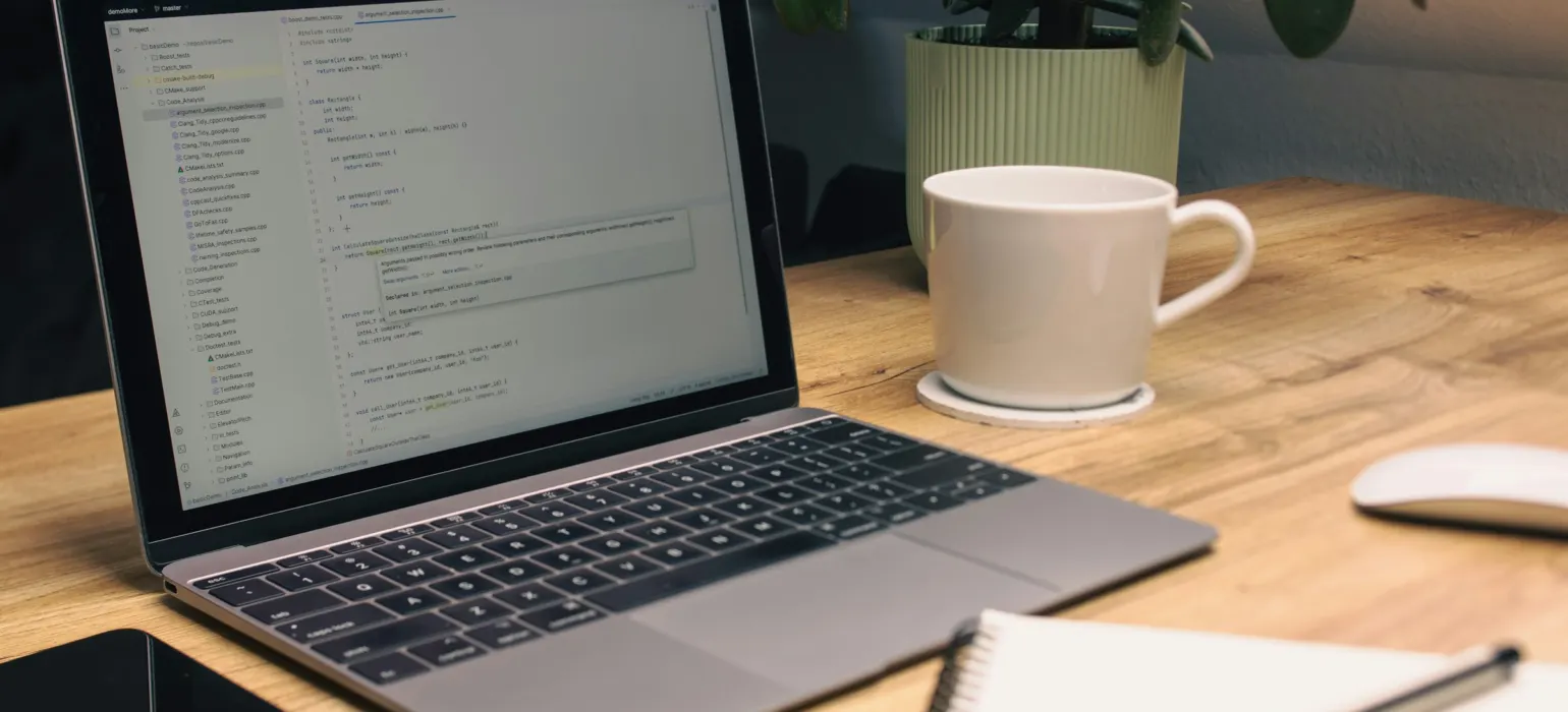 Laptop, notebook, phone, and mug on desk