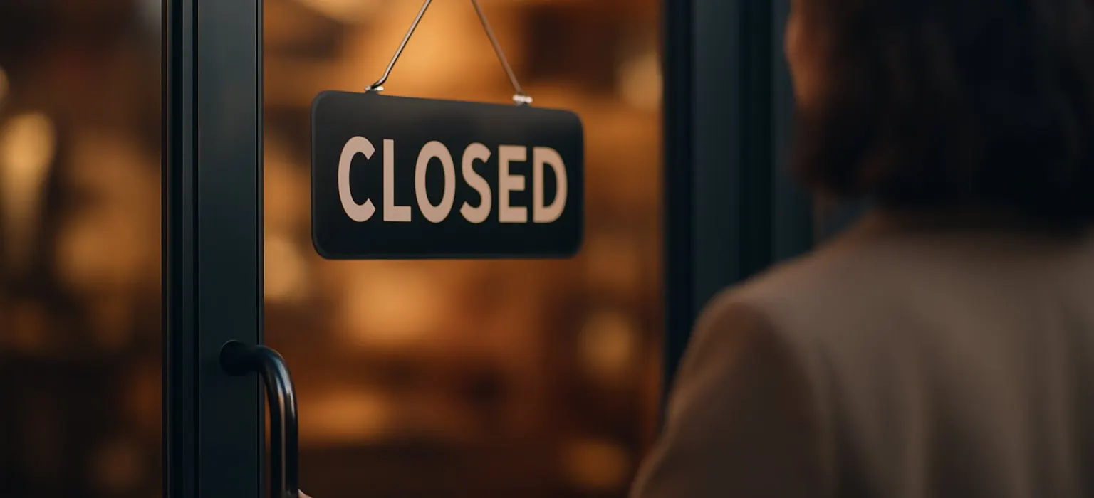 A closed sign hanging on a glass shop door in the evening light