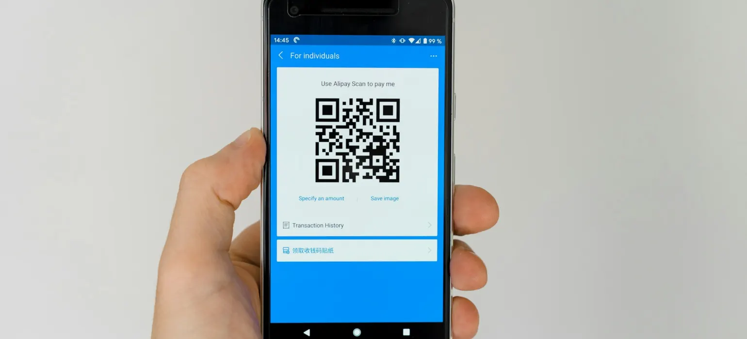 Hand holding a smartphone displaying a QR code