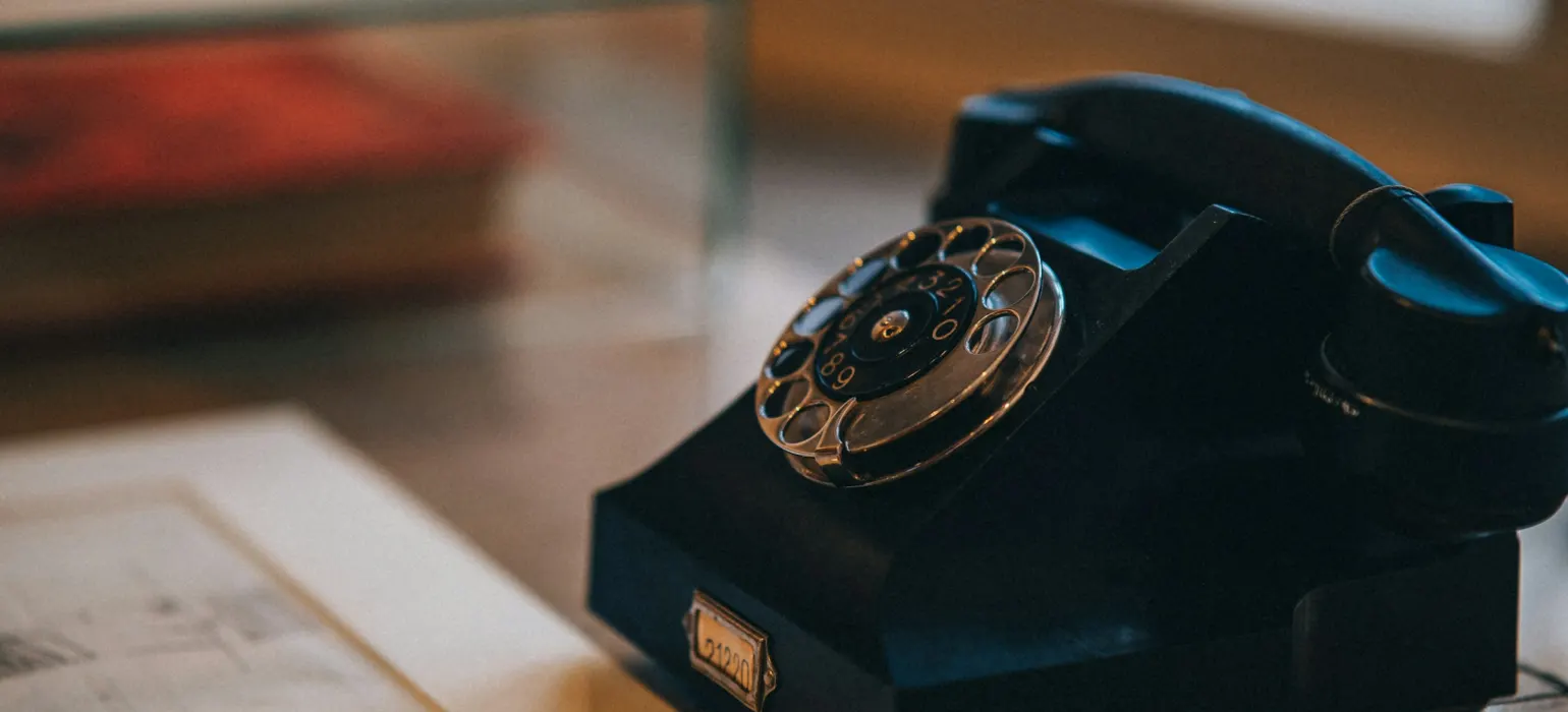An old - fashioned rotary telephone sits on a table