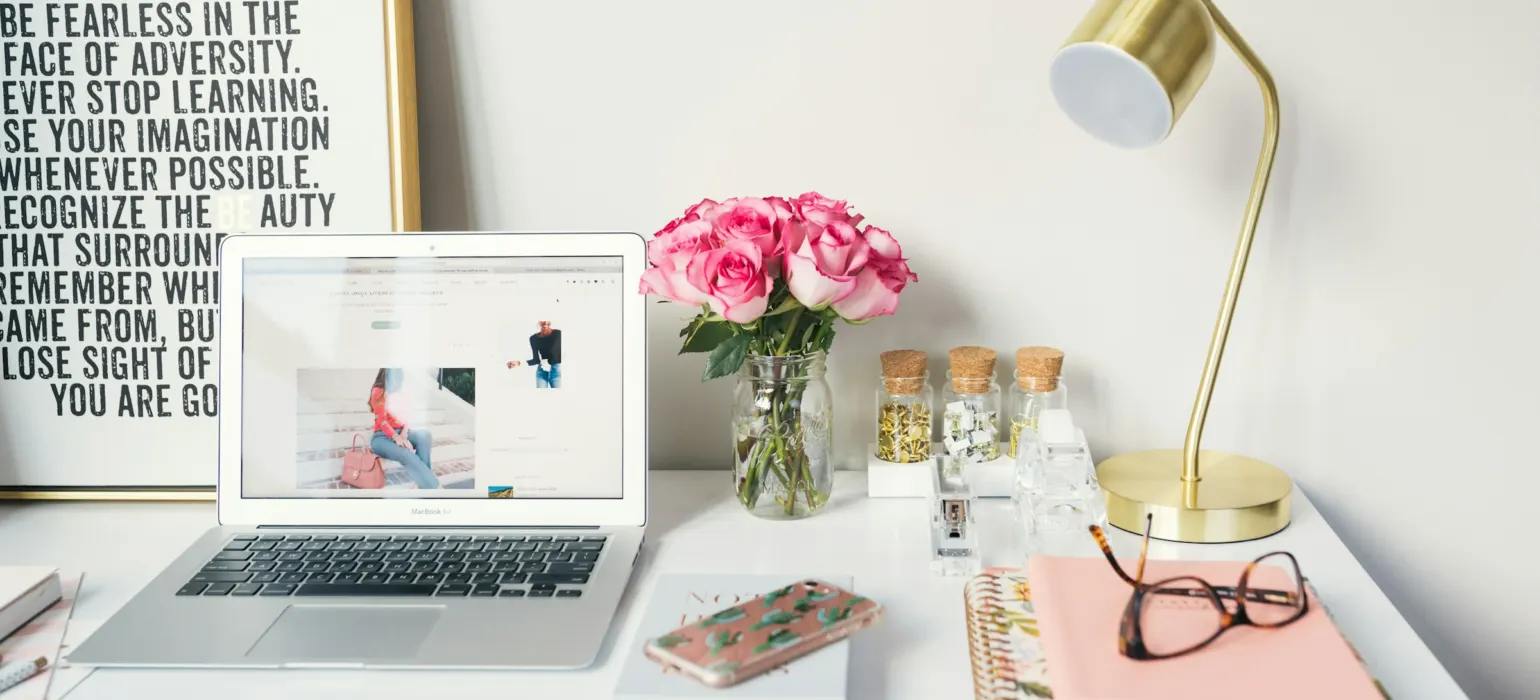 MacBook Air beside gold-colored study lamp and spiral books