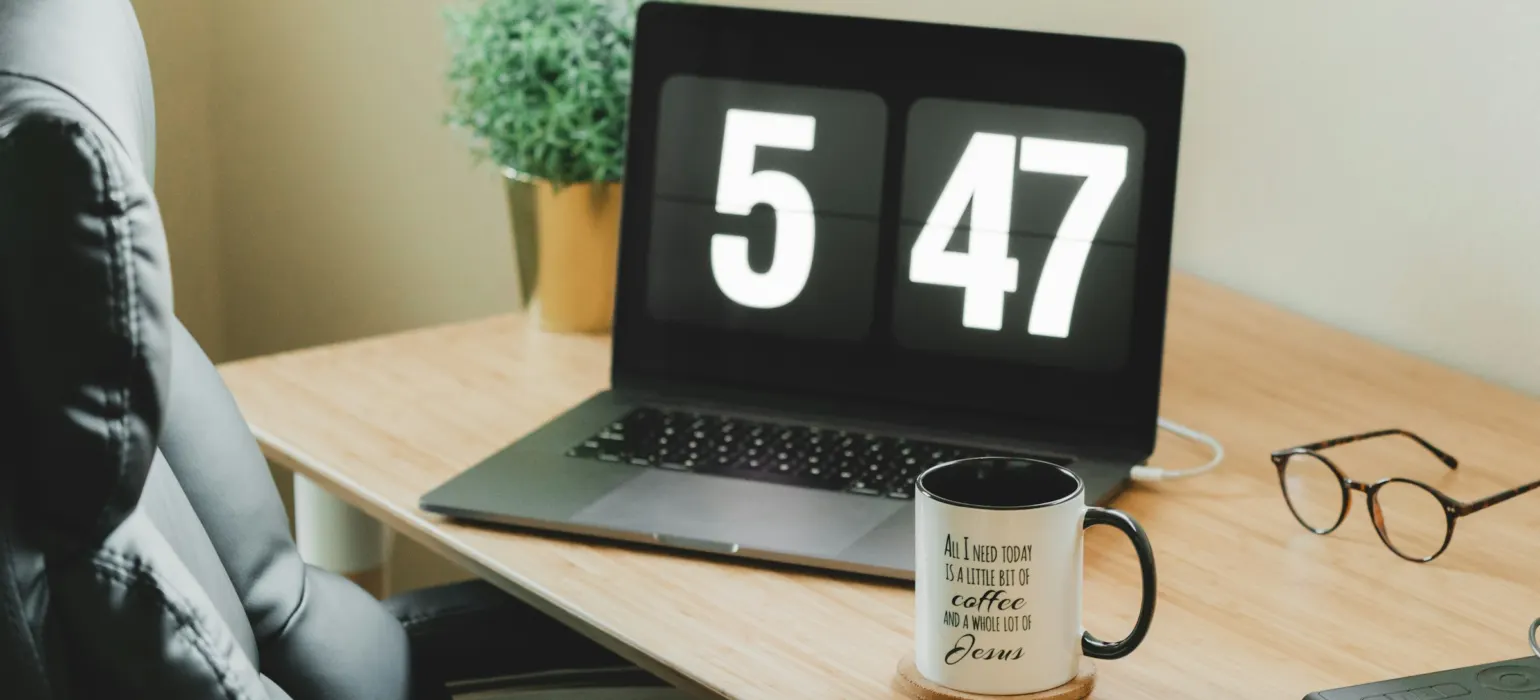 Turned-on MacBook Pro beside white and black ceramic mug