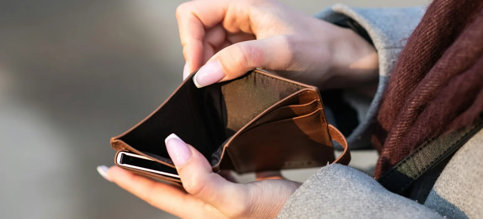 Hands holding empty wallet and phone