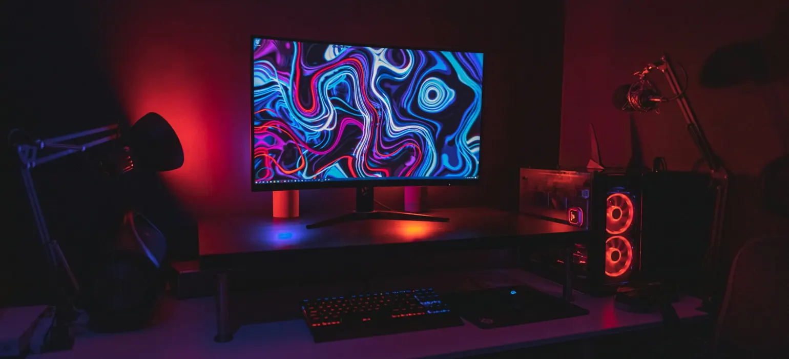 Black flat screen computer monitor turned on near black computer keyboard