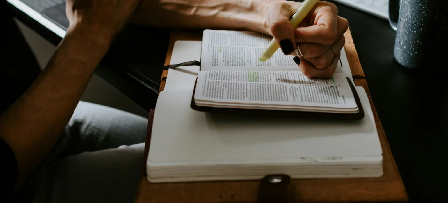 Person holding white pen writing on white notebook