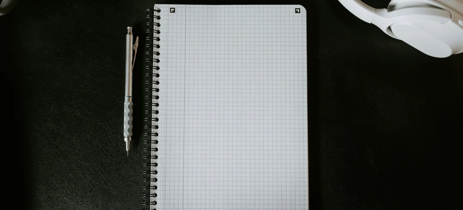 A notepad with a pen on top of it next to a mug