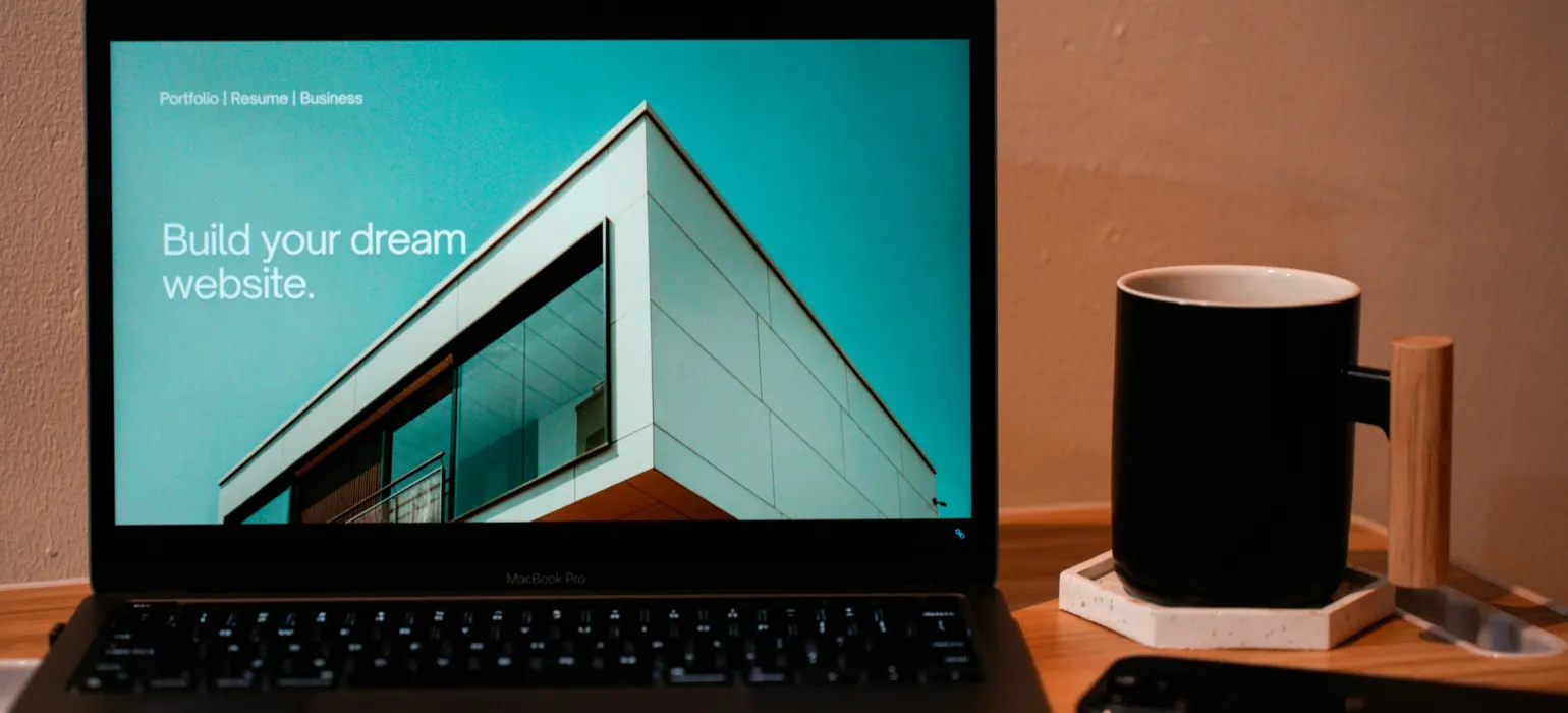 Laptop showing a website builder on a wooden desk