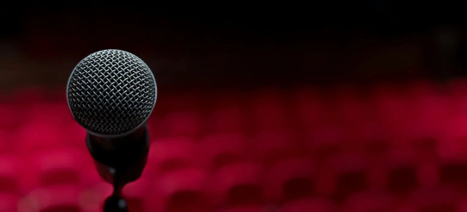 A microphone on a stand in front of a red background