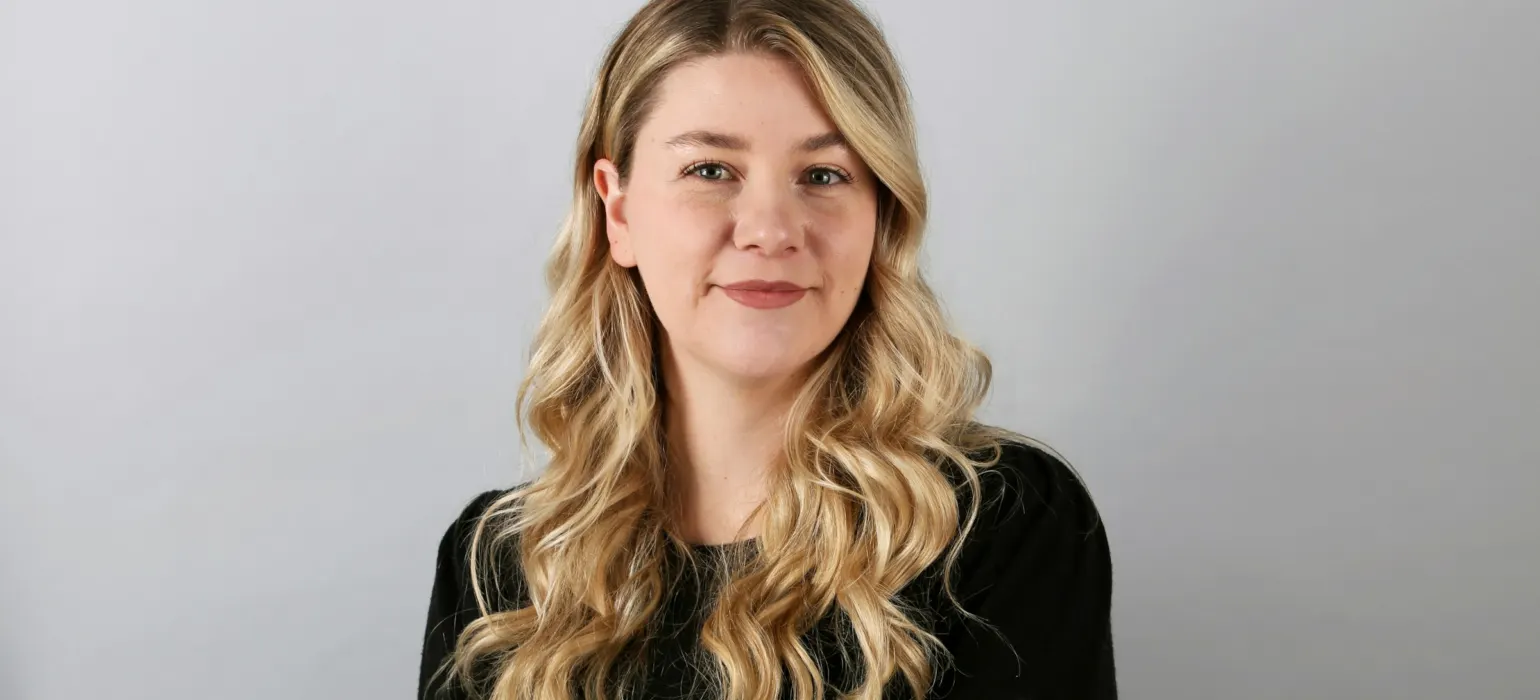 Professional headshot of a smiling woman against a plain background