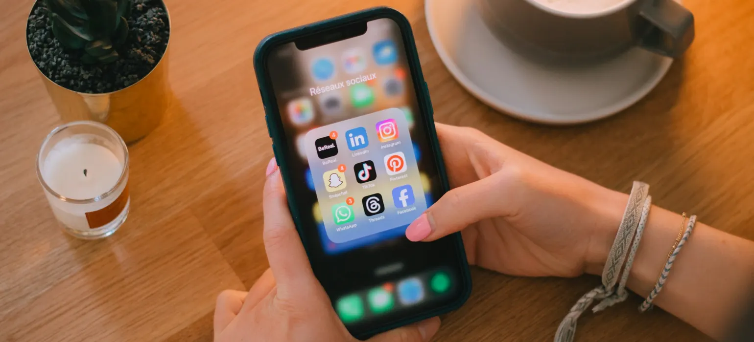 Hands holding a smartphone showing social media apps