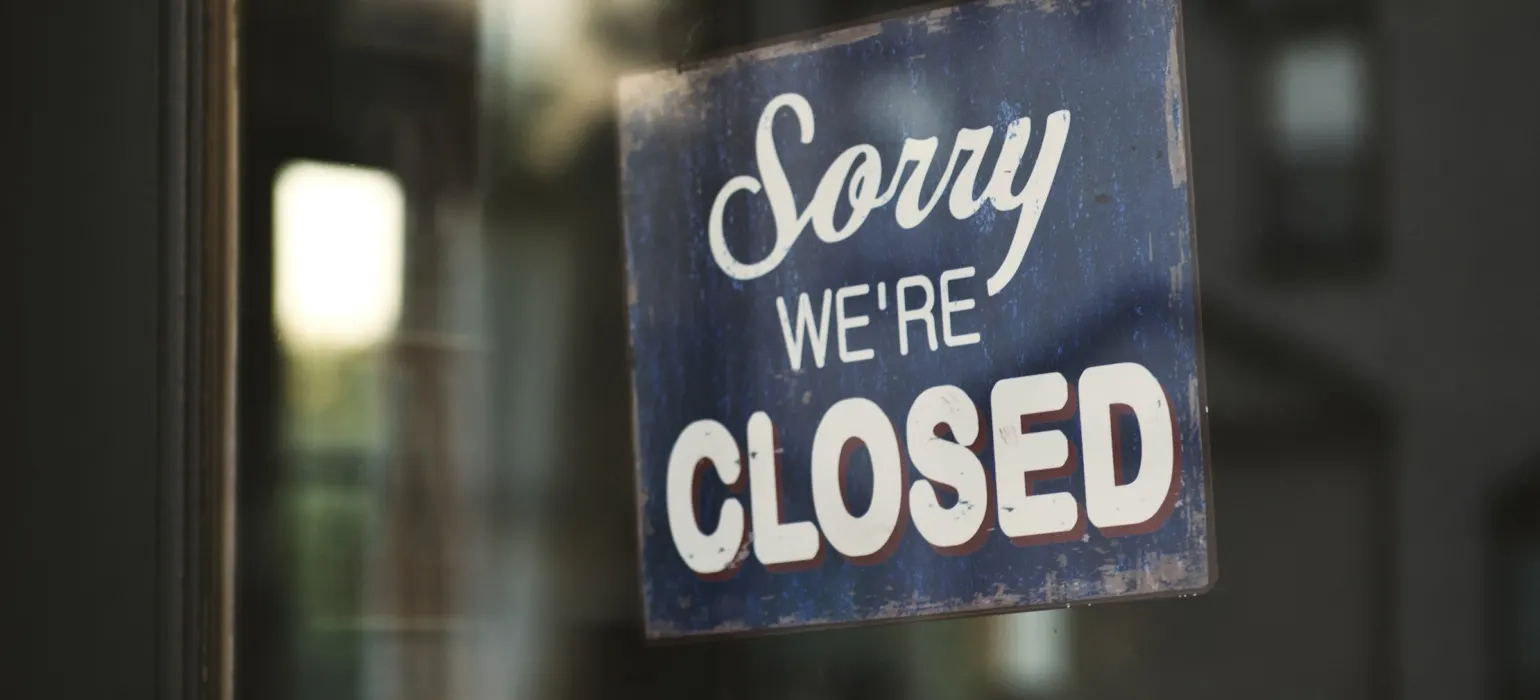 Sorry we're closed sign hanging on a glass door