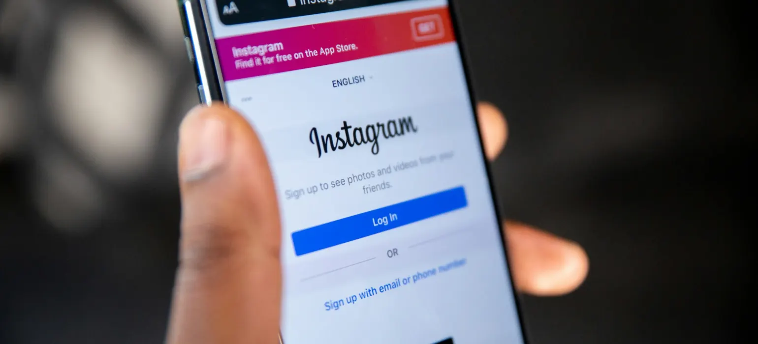 Hand holding a smartphone showing the Instagram login screen