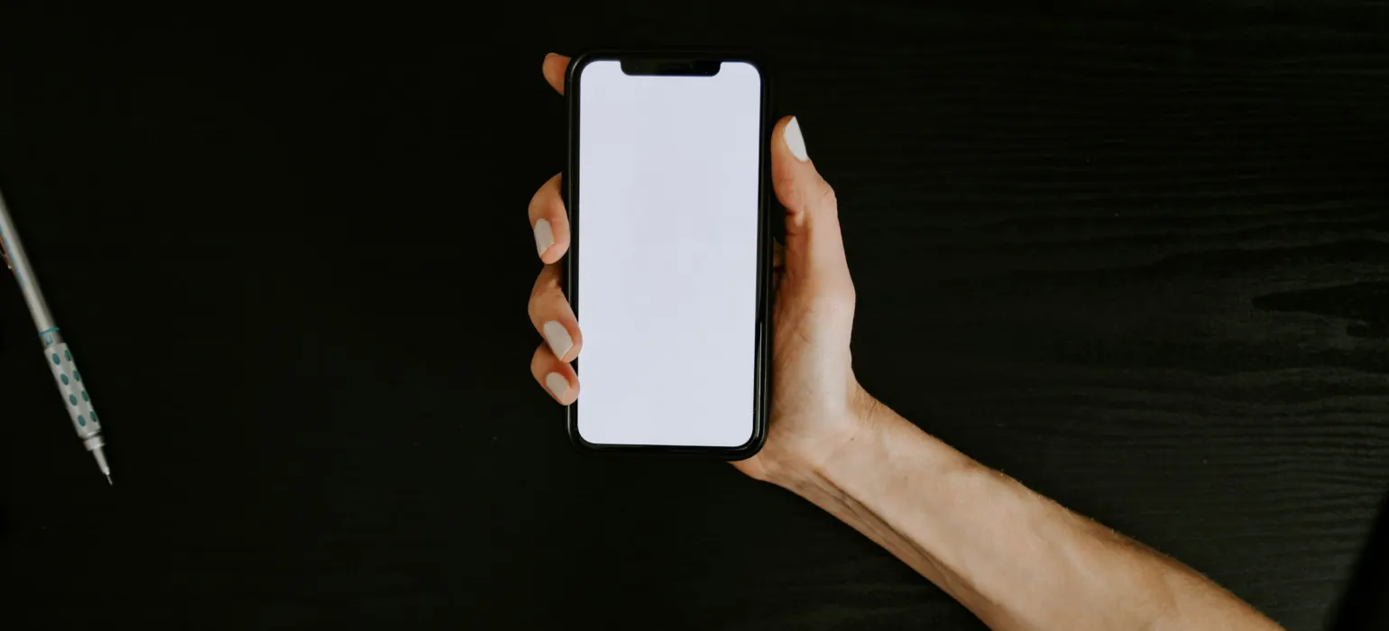 Hand holding a smartphone against a dark background