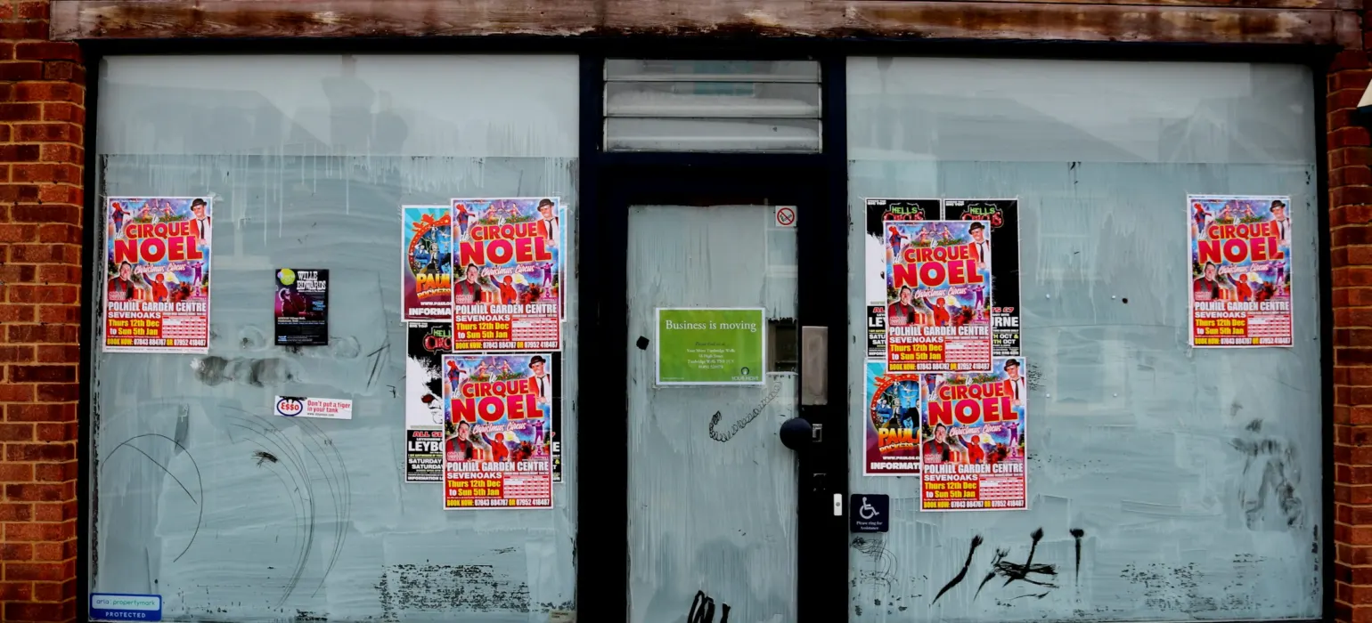 Empty shopfront with papered windows and a faded sign