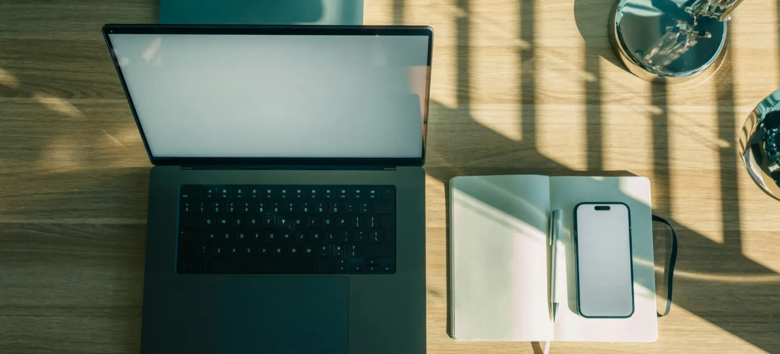 Laptop, phone, and notebook on a wooden desk