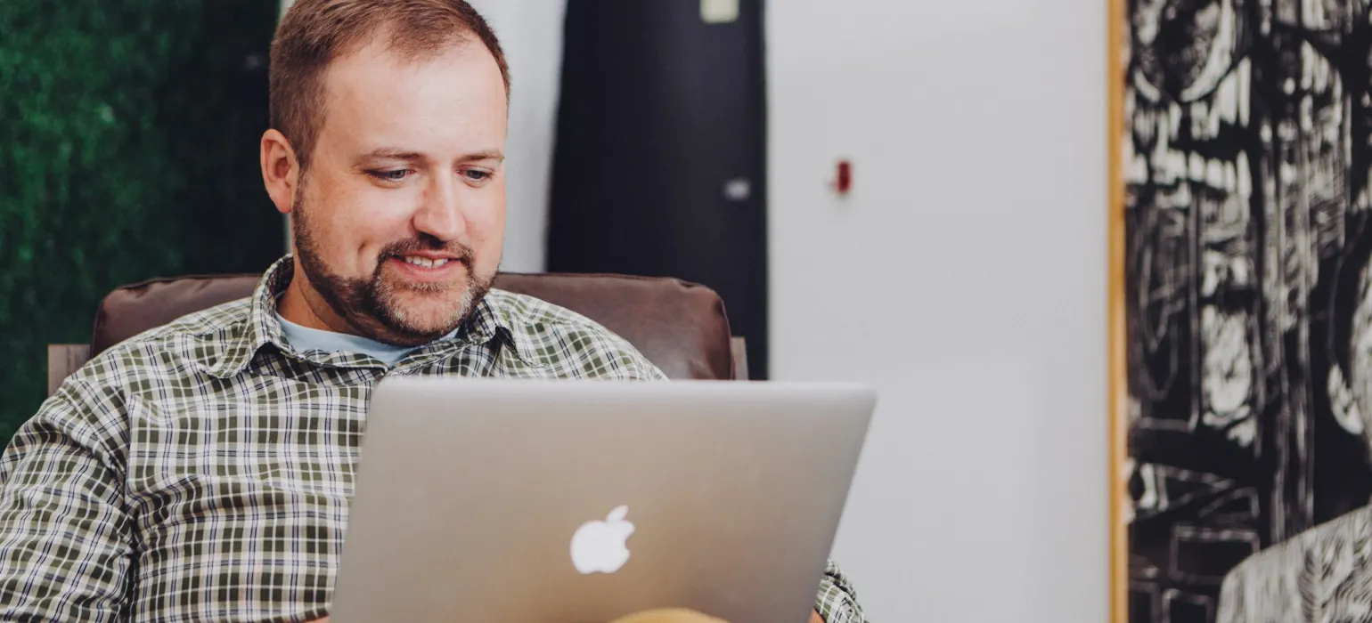 A smiling business owner typing on a laptop