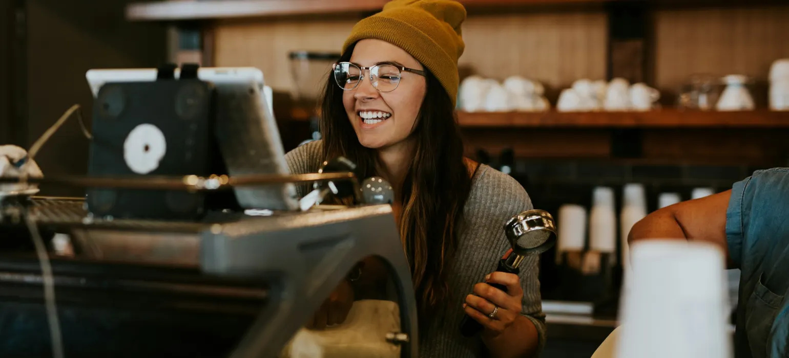 Smiling barista working the espresso machine in a cafe