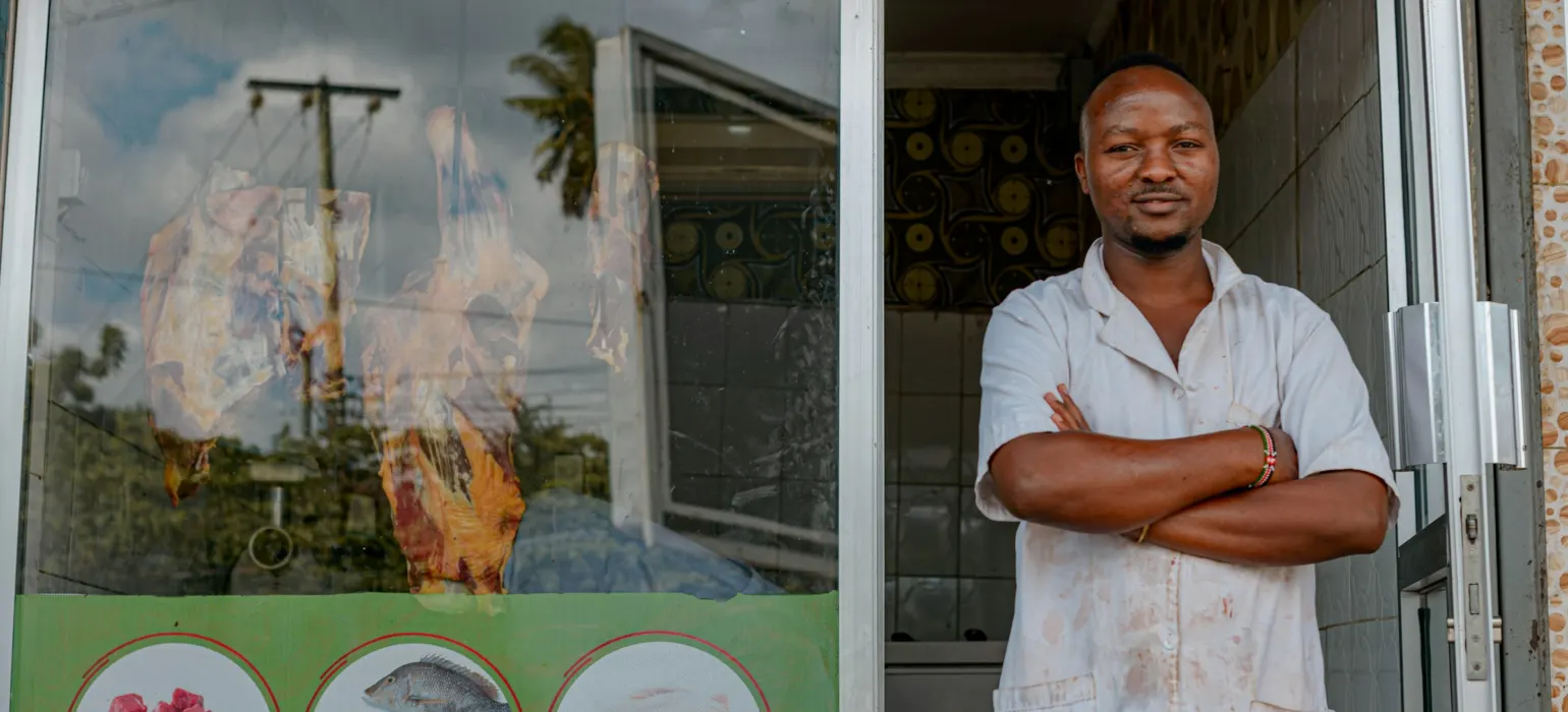 A shop owner standing in the doorway of his butcher shop