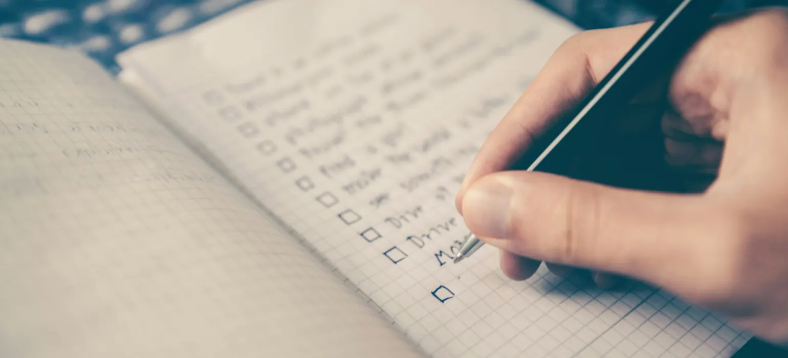 Person writing bucket list on book