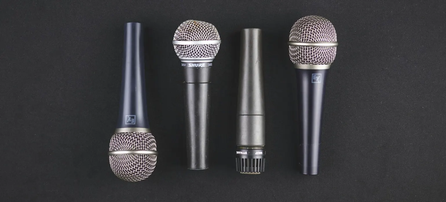 Four microphones laid side by side on a dark surface