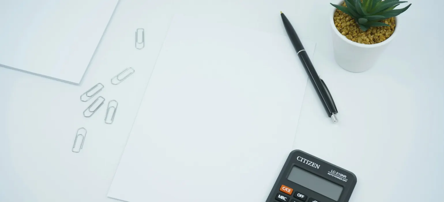 Black calculator beside black pen on white printer paper