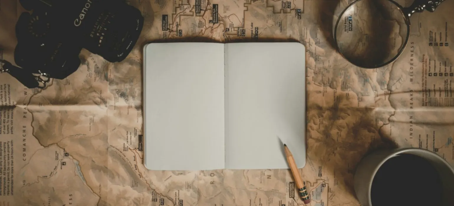 A notebook, camera and magnifying glass on an old map