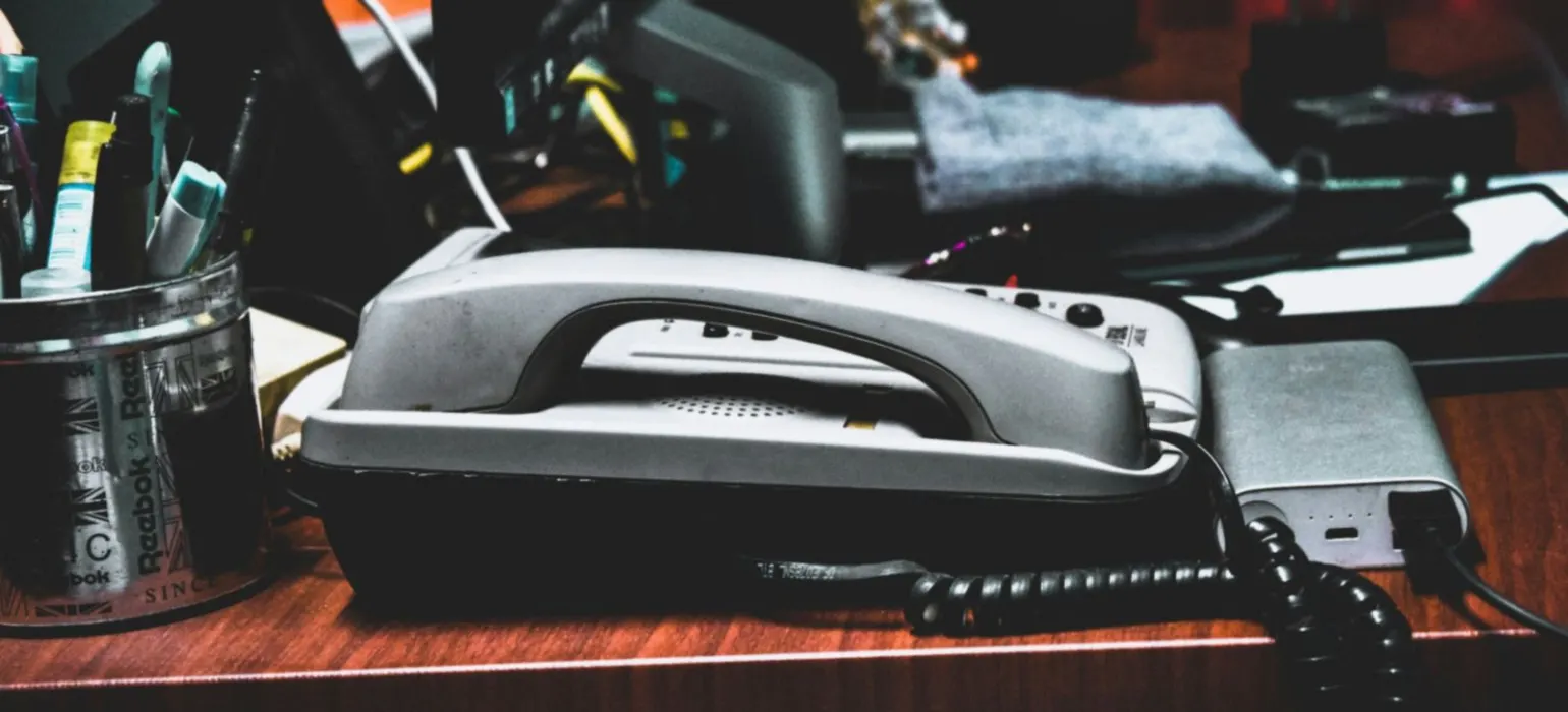A desk with a phone, pencils, pens, and other office supplies