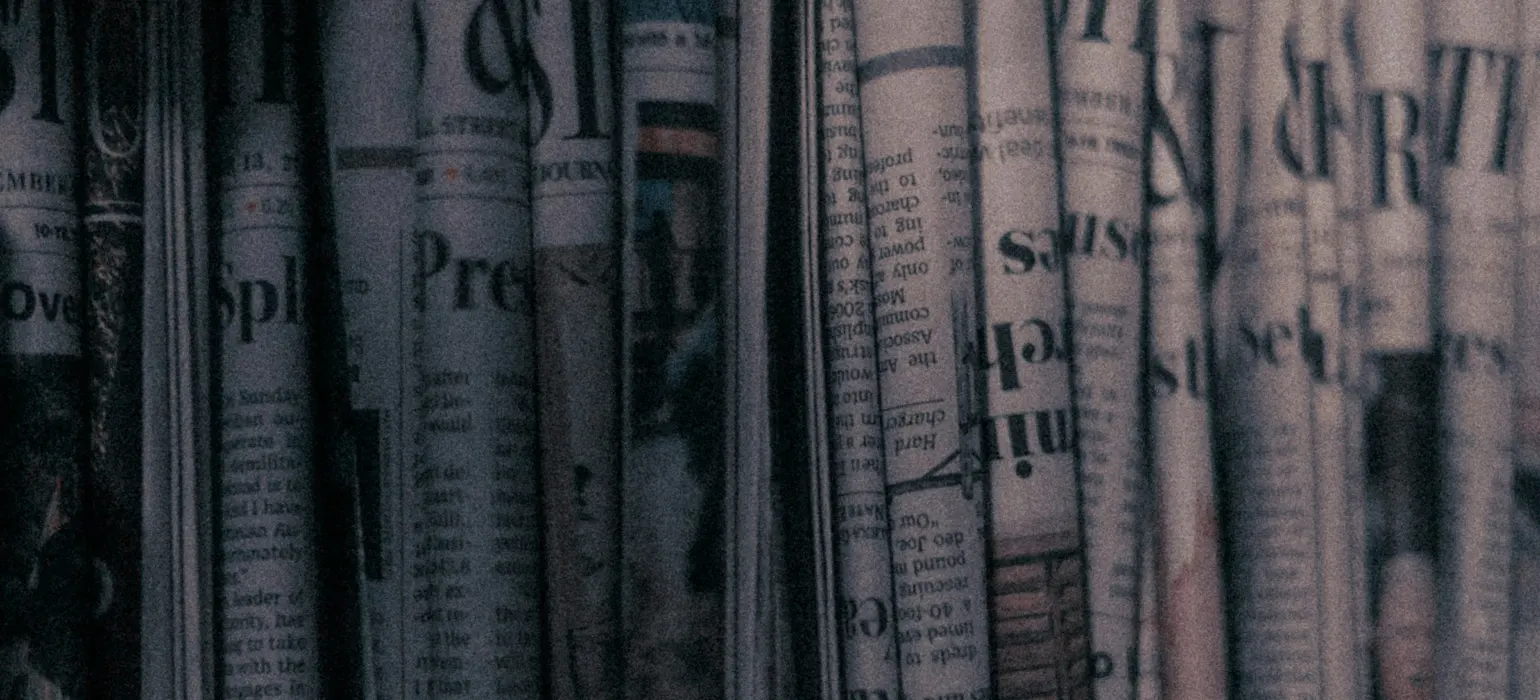 A row of newspapers sitting on top of a shelf