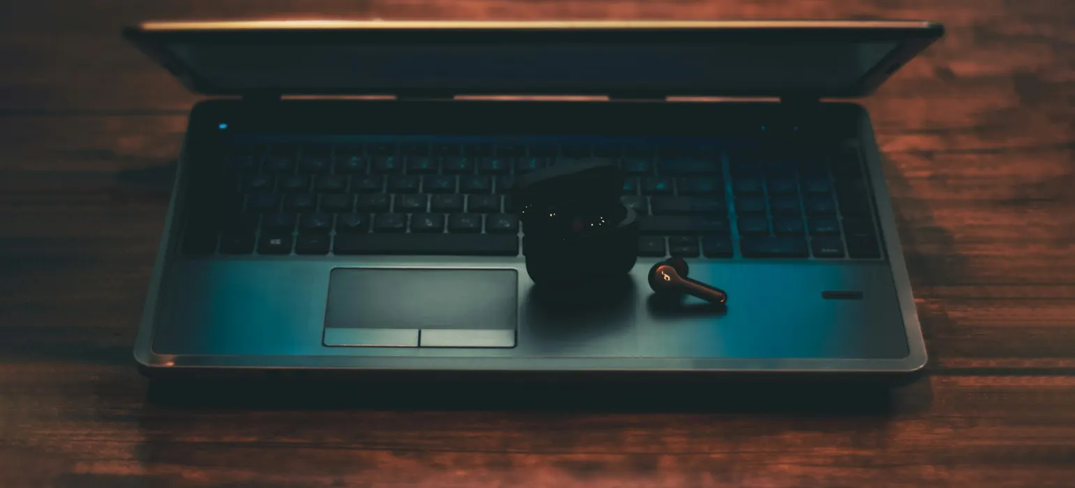 Black and gray laptop computer with black corded mouse on brown wooden table