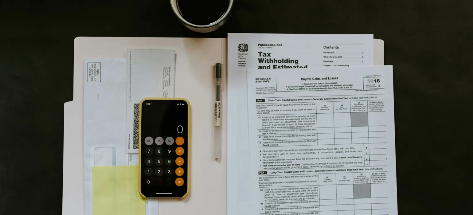 Black Android smartphone near ballpoint pen, tax withholding certificate on top of white folder