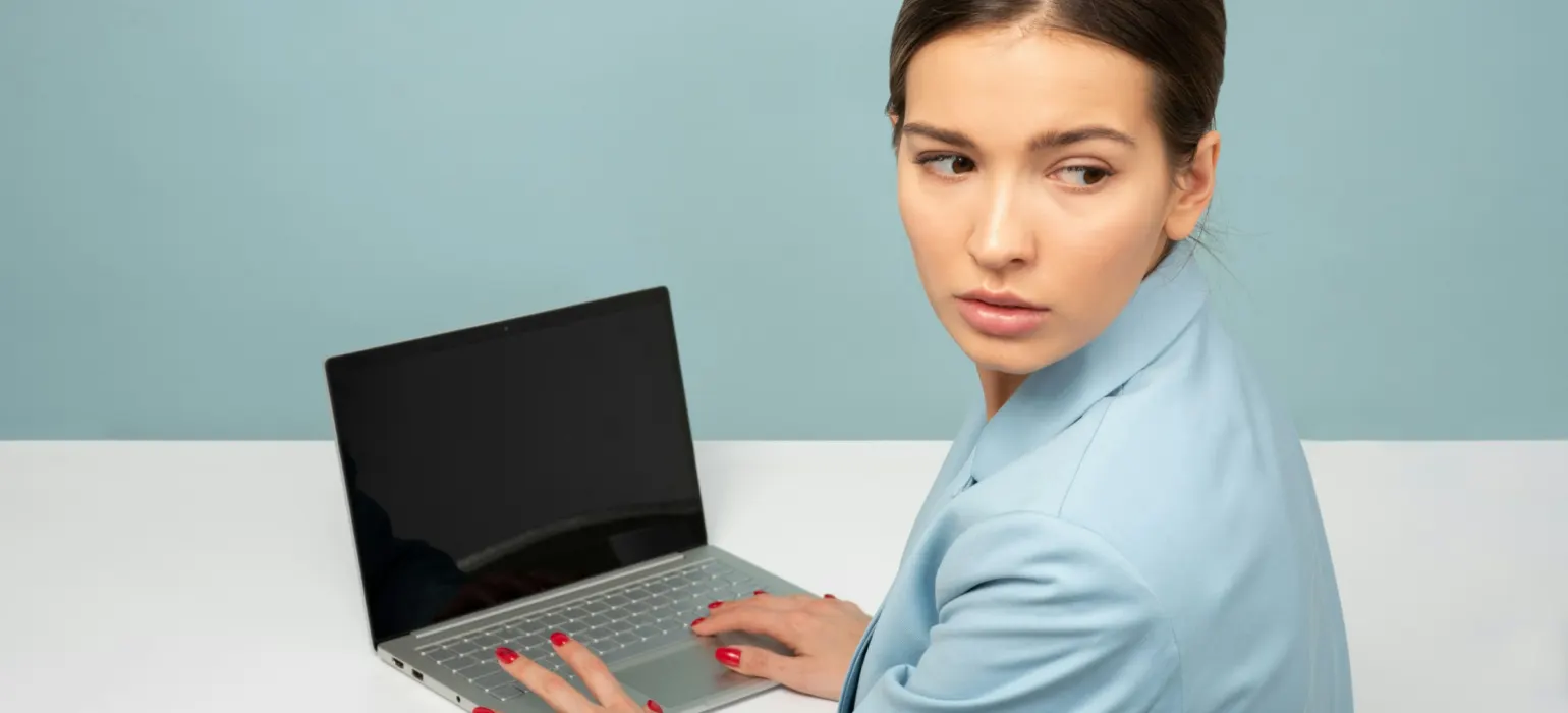 Professional woman at a laptop glancing to the side with concern