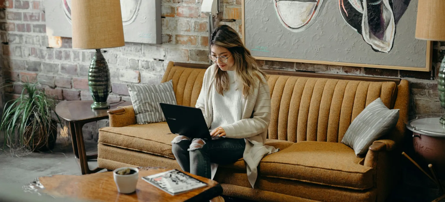 A freelancer working on a laptop on a sofa