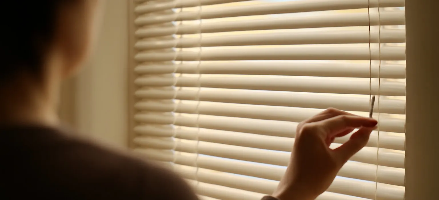 Closed window blinds with warm afternoon light filtering through the slats