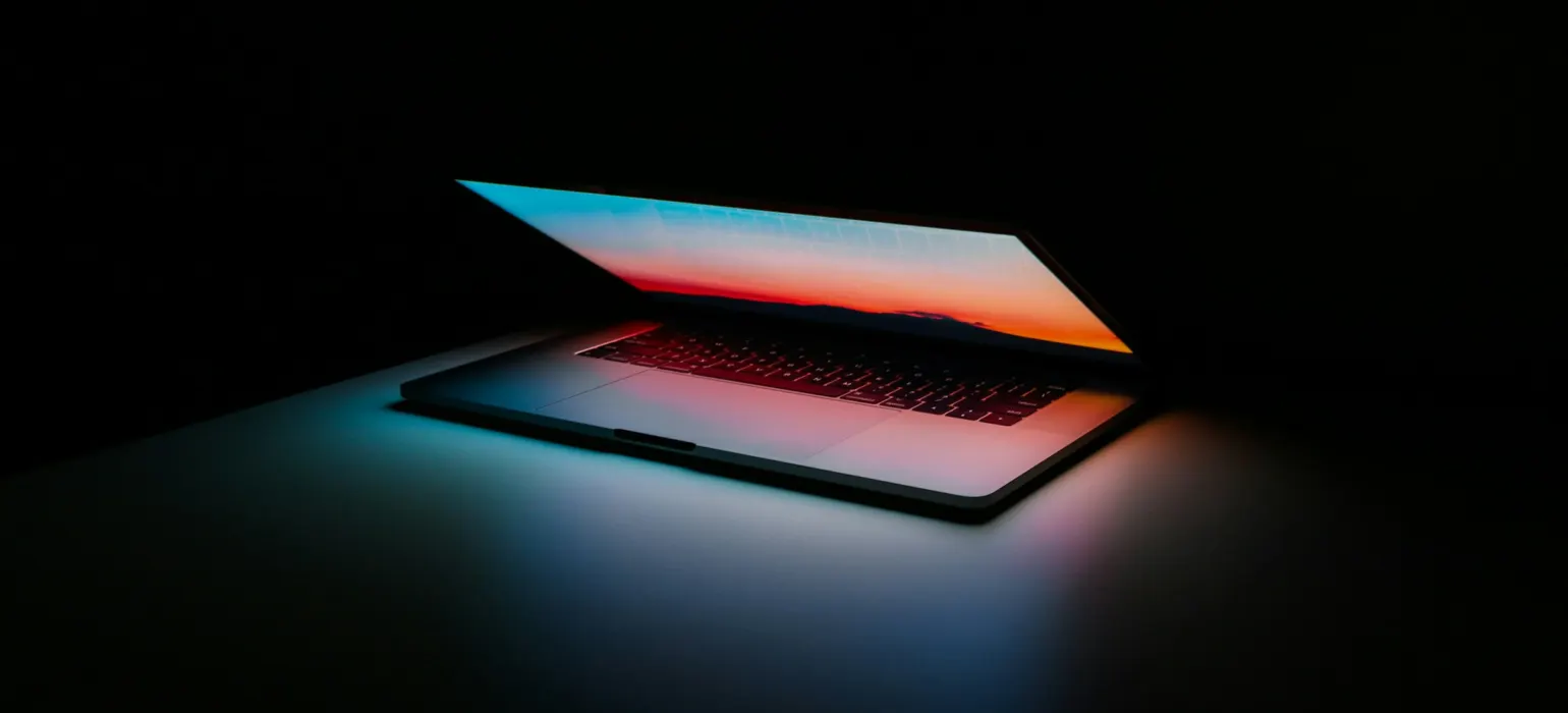 Laptop glowing on a dark surface