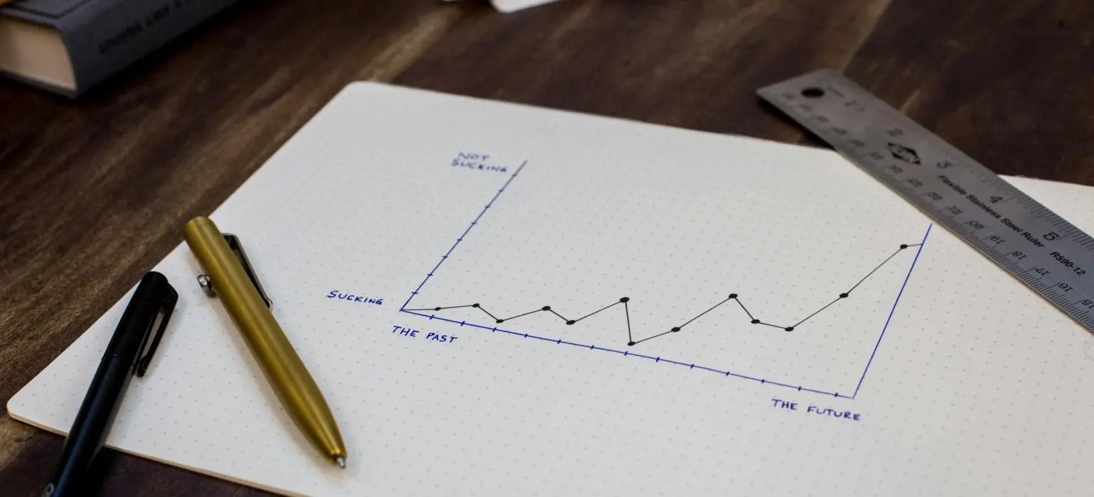 Hand-drawn line chart on paper next to a pen