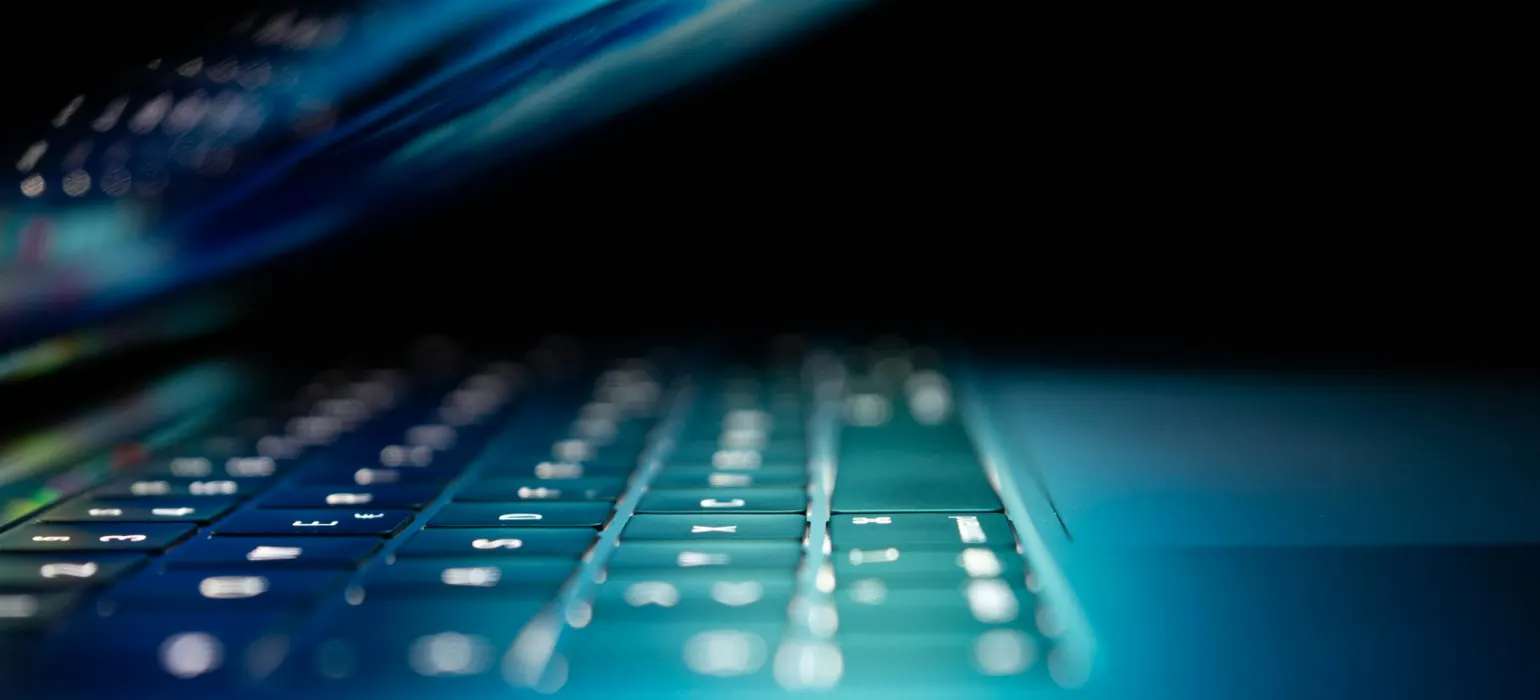 A laptop keyboard lit in blue light