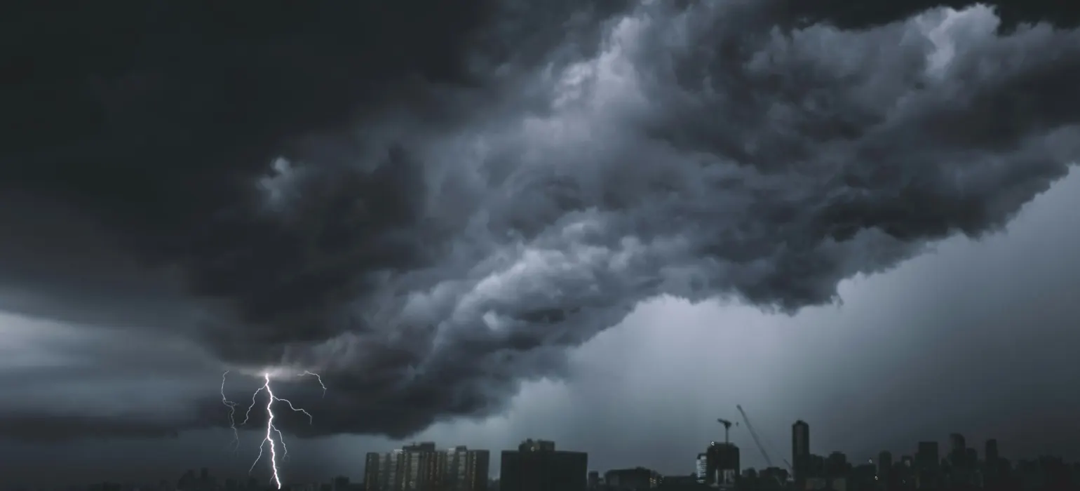 Dark storm clouds and lightning over a city skyline