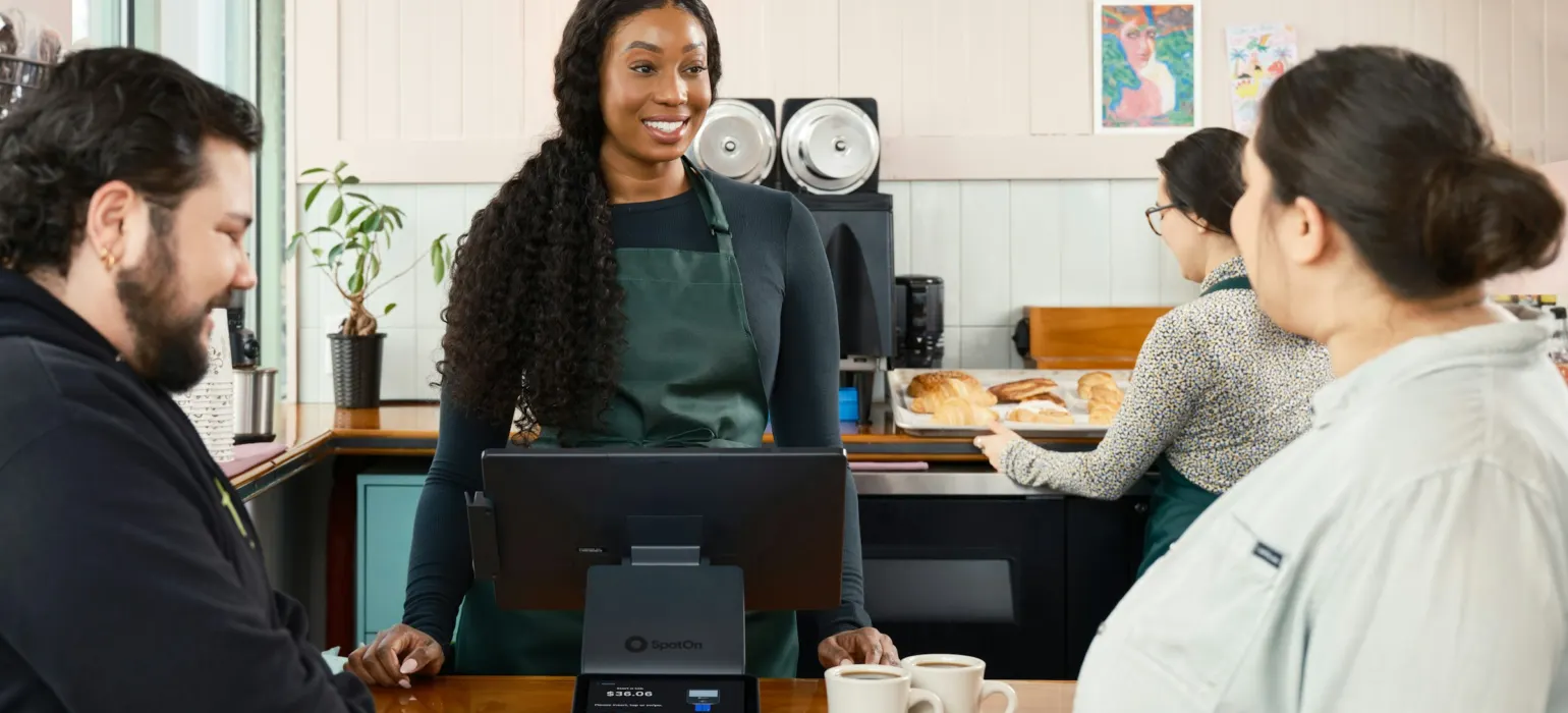 Smiling cafe employee serving customers at the counter