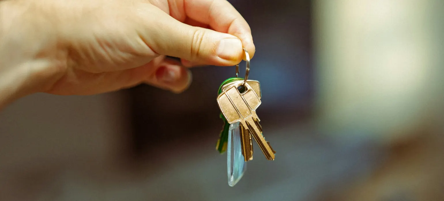 A hand holding out a set of keys